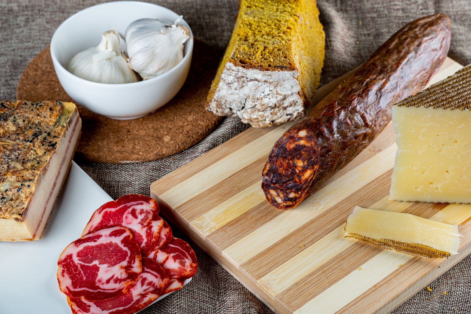 Closeup shot of a piece of parmesan cheese Ventricina sausage and bread on a cutting board